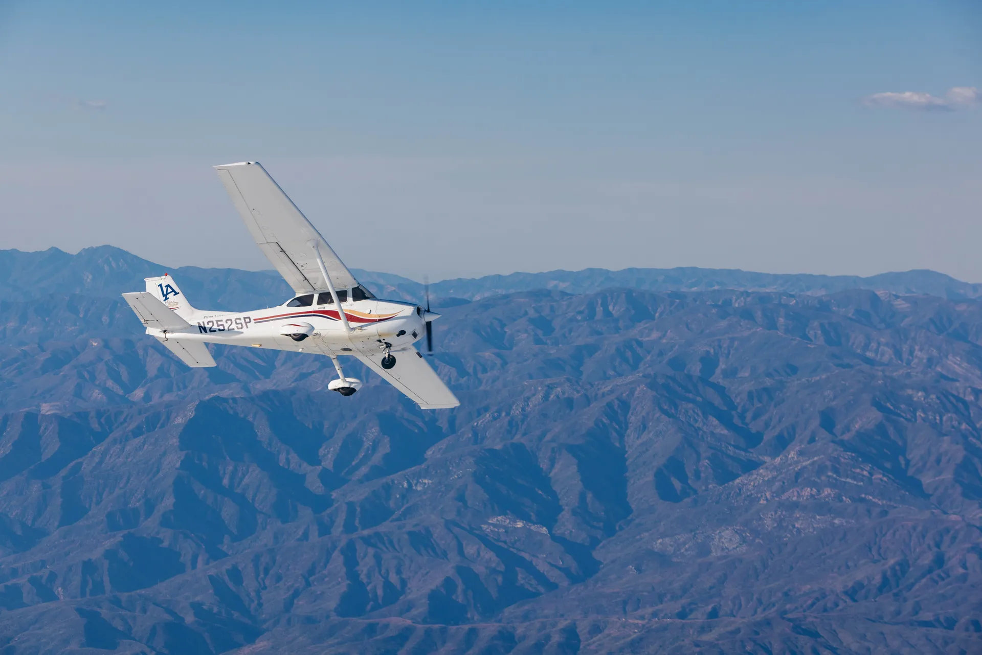 Photograph of an LA Flight Academy plane flying over mountains