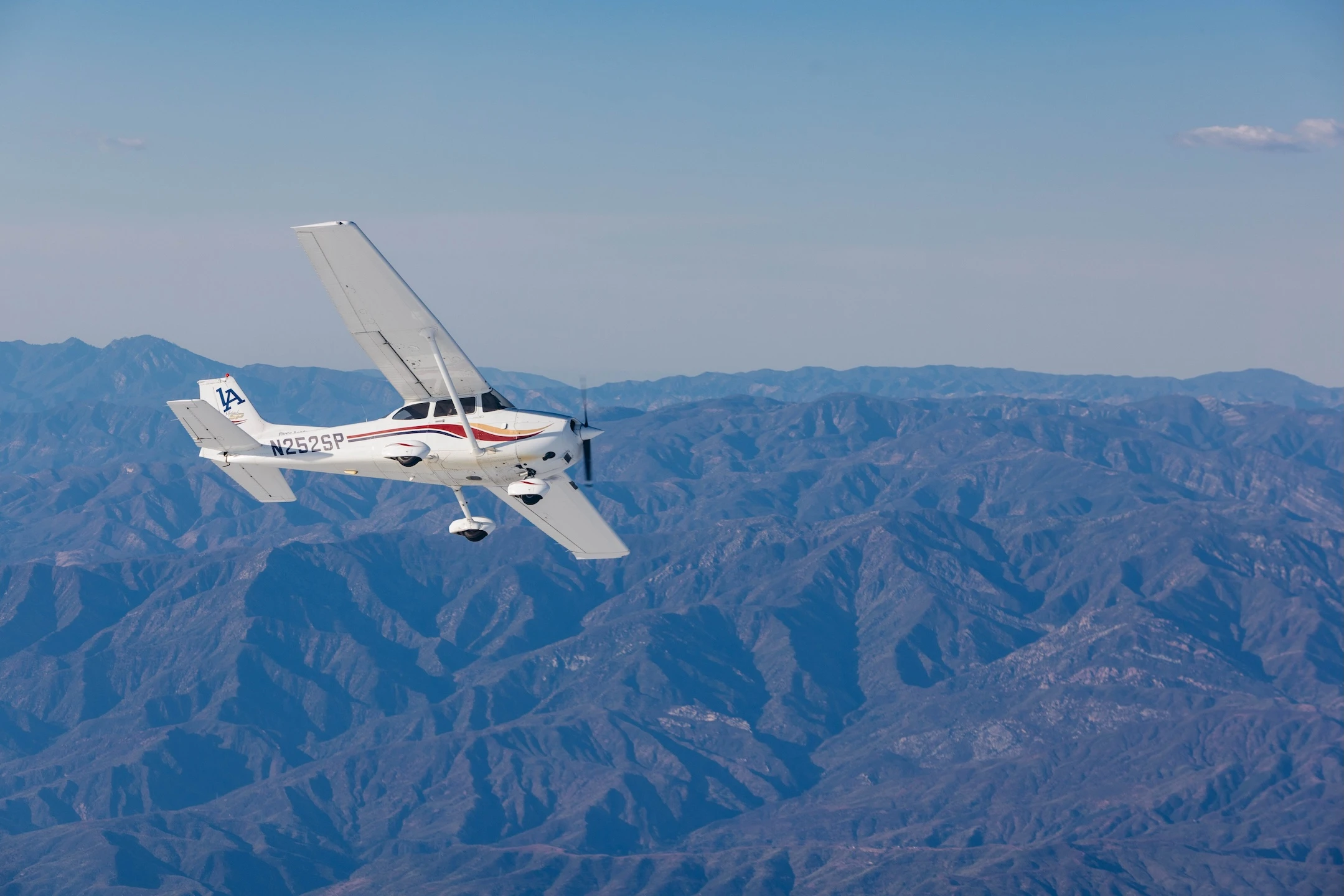 LA Flight Academy Piper Archer taking off from Van Nuys Airport past parked business jets