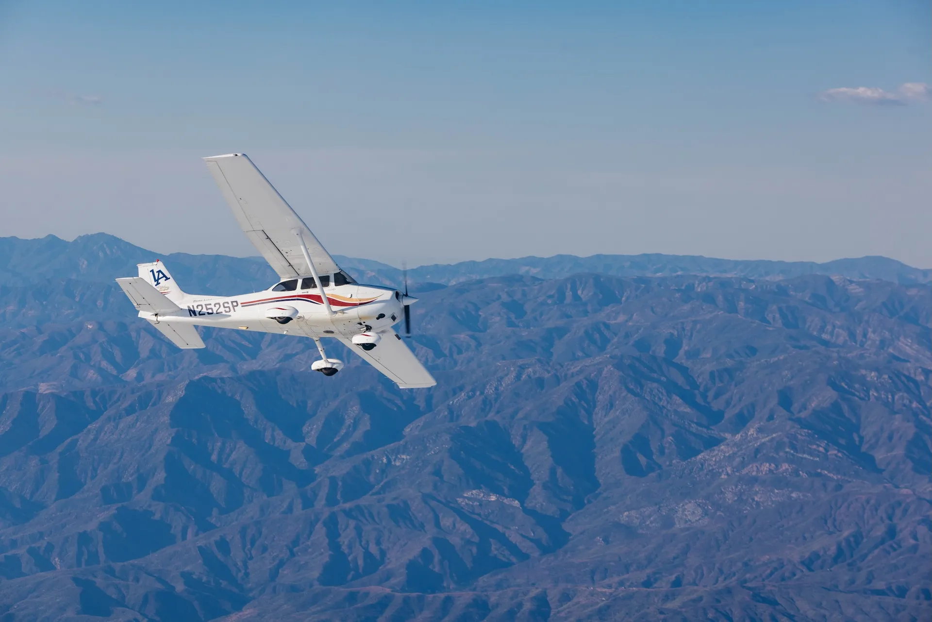 Photograph of an LA Flight Academy plane flying over mountains