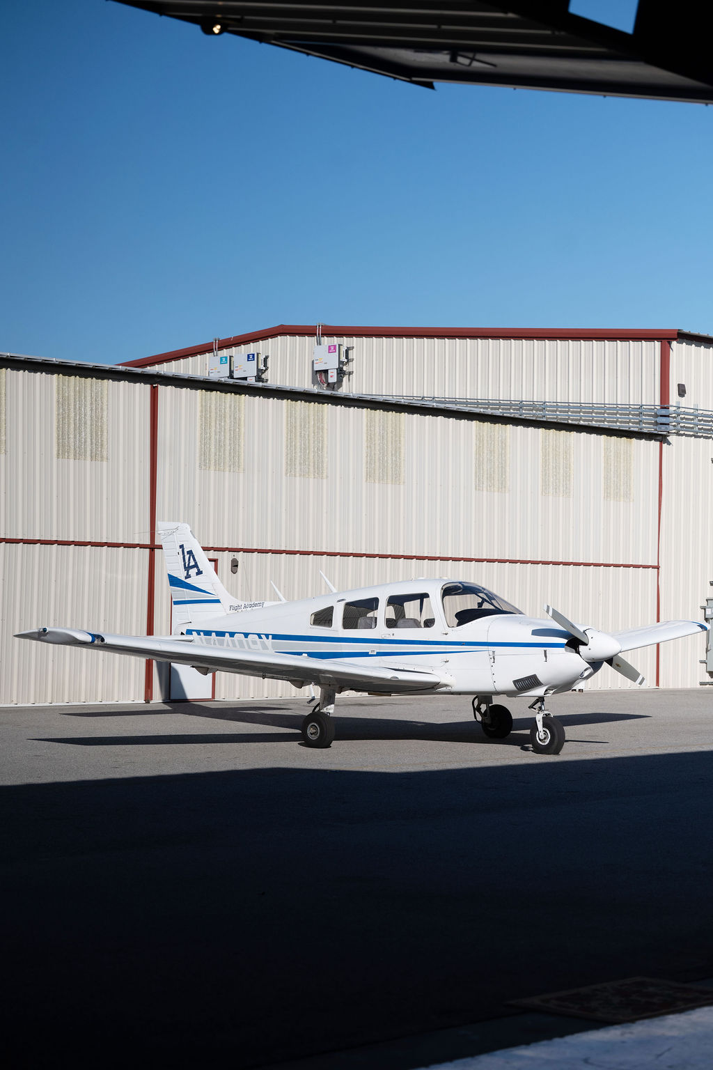 Side view of a Piper Archer II training aircraft at LA Flight Academy in Van Nuys